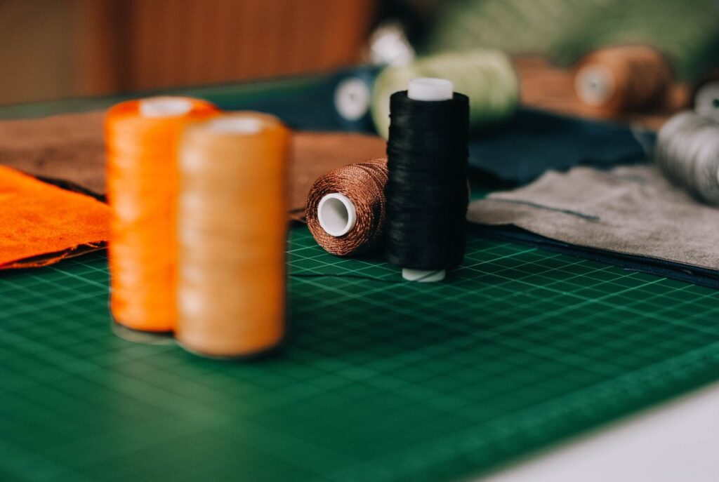 Colorful sewing threads on a patterned cutting mat in a craft room, perfect for textile projects.
