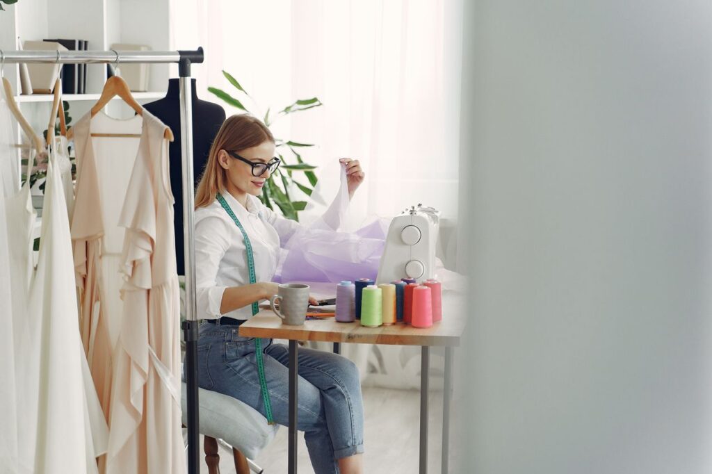Female designer sewing in a modern studio with fabrics and sewing machine.