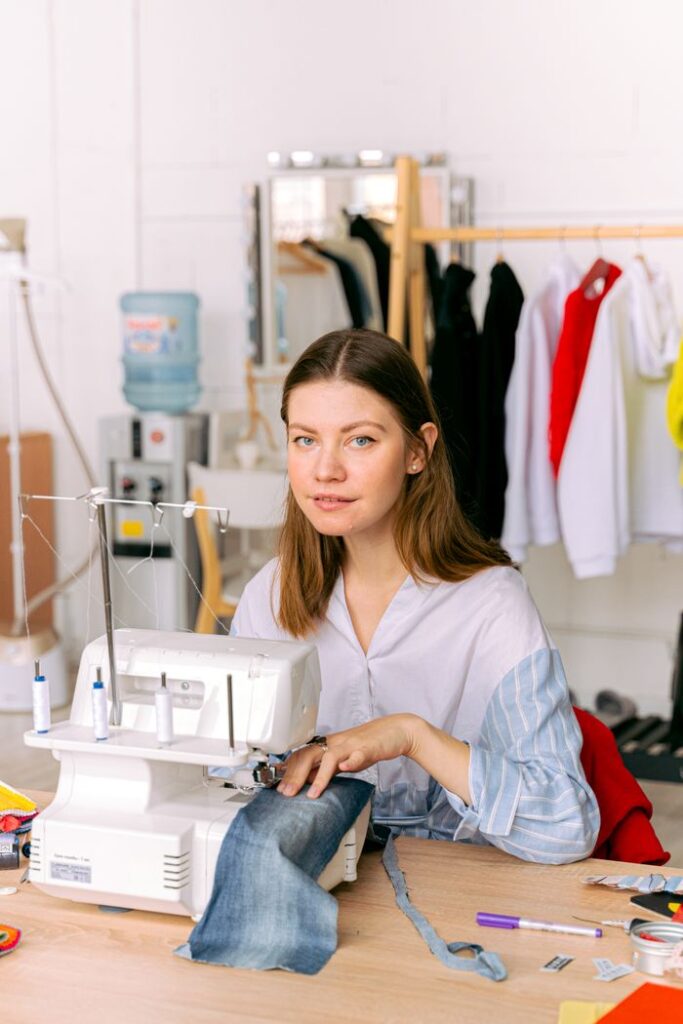 Young woman using a sewing machine in a bright, organized workspace for hobby or profession.